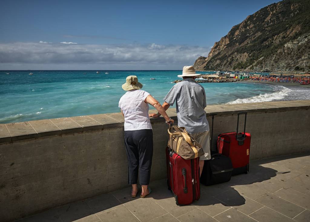 Casal-viajando Casal viajando. Os dois estão em um ponto turístico observando a vista ensolarada, e com malas nas mãos.