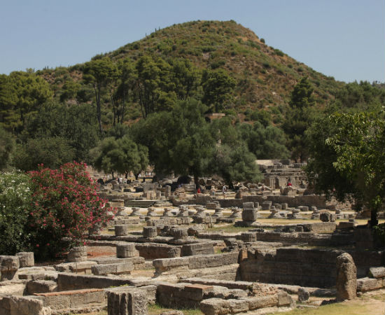 Os Jogos Olímpicos começaram em 776 a.C. como forma de homenagear Zeus - data que também marca o início da chamada Grécia antiga. A partir daí, os jogos passaram a ser realizados de quatro em quatro anos, em Olímpia. A primazia dessa cidade sobre as outras na organização dos jogos está fundamentada na mitologia. Filho de Zeus, o herói Hércules teria inaugurado os Jogos Olímpicos como forma de comemorar o sucesso de um de seus 12 trabalhos: a limpeza dos estábulos de Audias, rei de Elis. Essa lenda foi representada em Olímpia pelo escultor Fídias, que, em 440 a.C., foi o responsável pela construção do mais importante templo em homenagem a Zeus, que se transformou numa das Sete Maravilhas do mundo antigo e tem uma estátua com 12 metros de altura do deus. Ali, os campeões eram condecorados e se faziam os principais sacrifícios e as maiores oferendas. (Na foto, Olímpia, hoje um importante destino turístico) Os Jogos Olímpicos começaram em 776 a.C. como forma de homenagear Zeus - data que também marca o início da chamada Grécia antiga. A partir daí, os jogos passaram a ser realizados de quatro em quatro anos, em Olímpia. A primazia dessa cidade sobre as outras na organização dos jogos está fundamentada na mitologia. Filho de Zeus, o herói Hércules teria inaugurado os Jogos Olímpicos como forma de comemorar o sucesso de um de seus 12 trabalhos: a limpeza dos estábulos de Audias, rei de Elis. Essa lenda foi representada em Olímpia pelo escultor Fídias, que, em 440 a.C., foi o responsável pela construção do mais importante templo em homenagem a Zeus, que se transformou numa das Sete Maravilhas do mundo antigo e tem uma estátua com 12 metros de altura do deus. Ali, os campeões eram condecorados e se faziam os principais sacrifícios e as maiores oferendas. (Na foto, Olímpia, hoje um importante destino turístico)