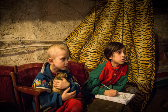 As crianças Pavel Makeev, de cinco anos de idade, e Raya Makeeva, de sete, esperam o almoço ficar pronto no porão de um centro cultural no leste da Ucrânia, onde vivem atualmente. A região tem sido fortemente atacada por forças ucranianas, obrigando a maioria dos moradores a fugir ou a se esconder em lugares como esse. As pessoas têm vivido no espaço desde junho de 2014. (Foto: Andrew Burton / Getty Images) As crianças Pavel Makeev, de cinco anos de idade, e Raya Makeeva, de sete, esperam o almoço ficar pronto no porão de um centro cultural no leste da Ucrânia, onde vivem atualmente. A região tem sido fortemente atacada por forças ucranianas, obrigando a maioria dos moradores a fugir ou a se esconder em lugares como esse. As pessoas têm vivido no espaço desde junho de 2014. (Foto: Andrew Burton / Getty Images)