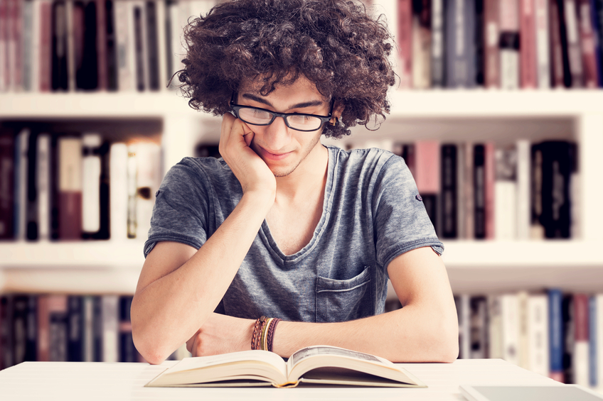 Young student reading  book in library