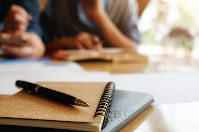 Estudantes, cadernos, caneta e papéis