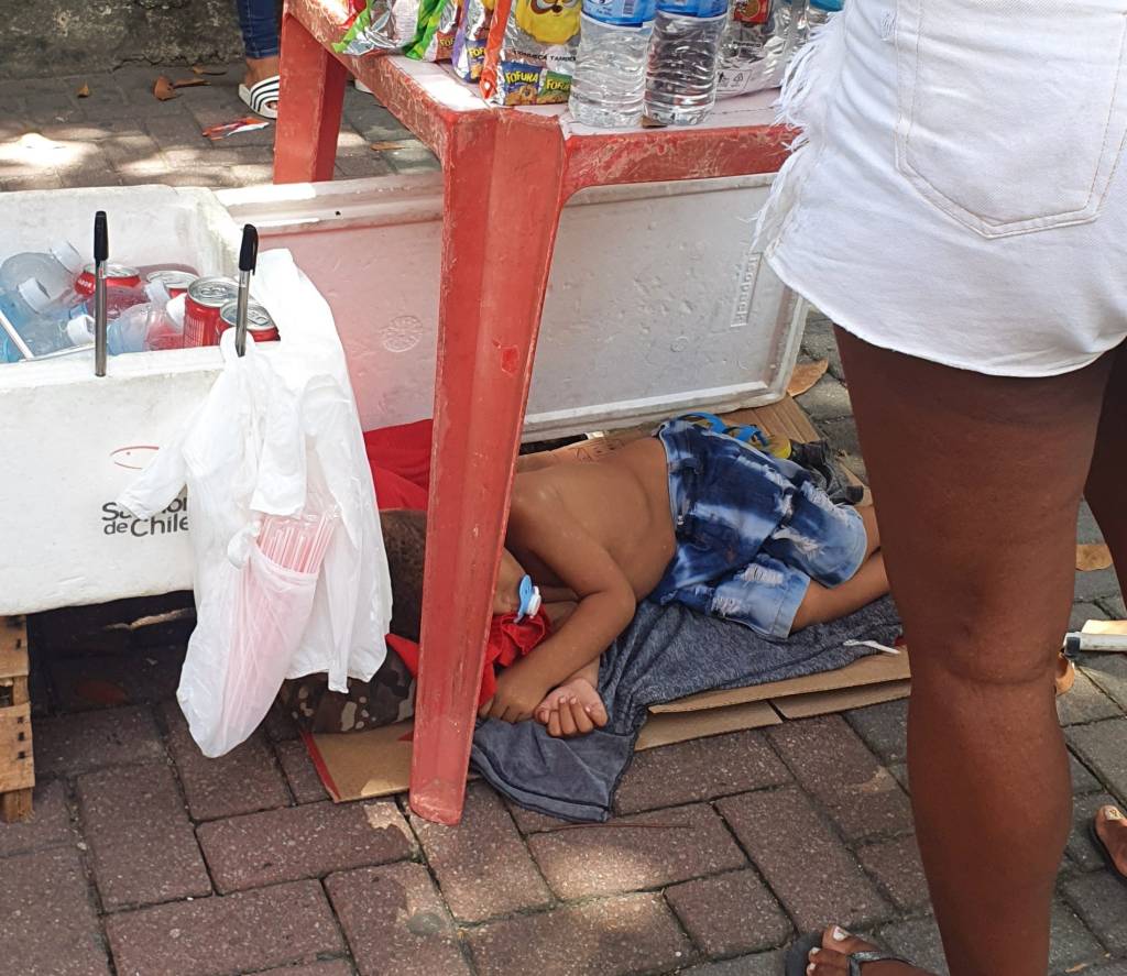 Ambulante na entrada do Enem Criança dorme sob banca de ambulante na entrada do Enem
