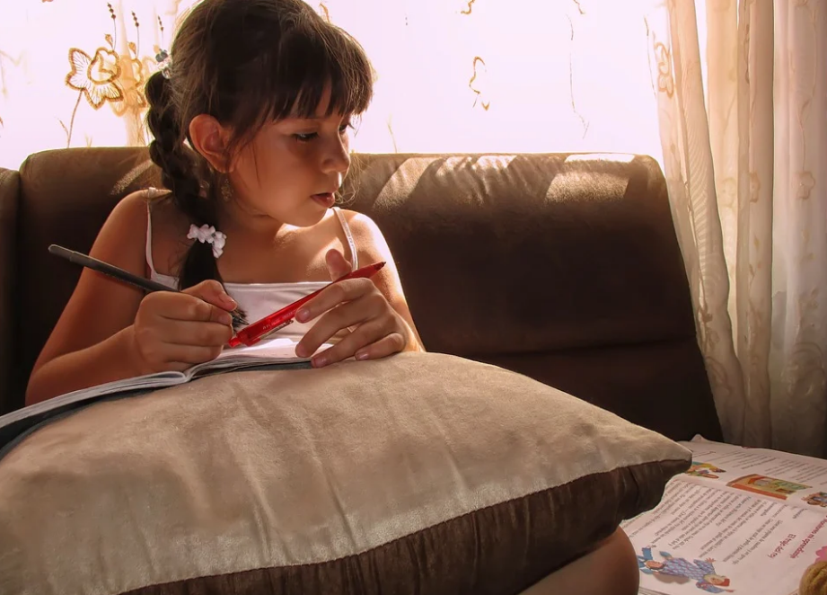 Menina estudando em casa Menina estudando em casa com livro didático