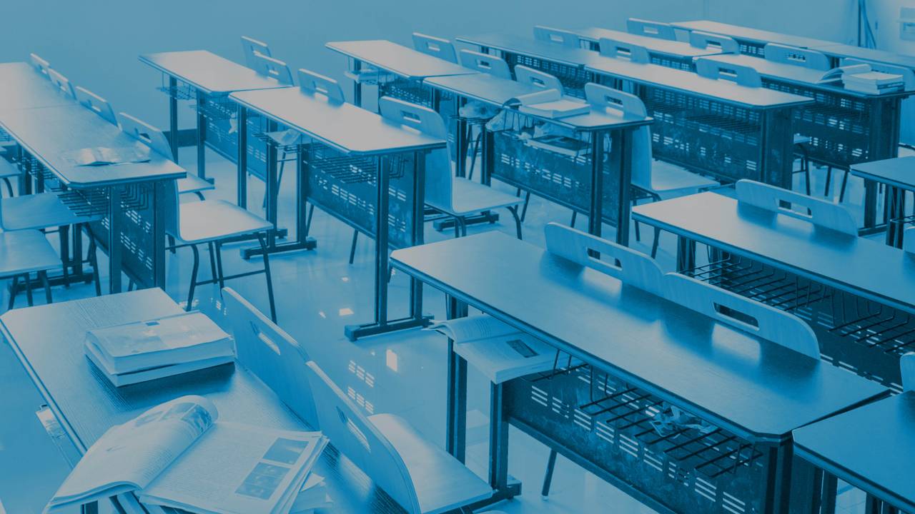 Sala de aula com carteiras e livros em cima das mesas. Com o filtro azul