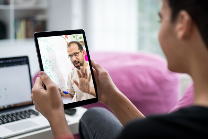 Estudante em uma aula online ouve os ensinamentos de um professor por meio de um tablet