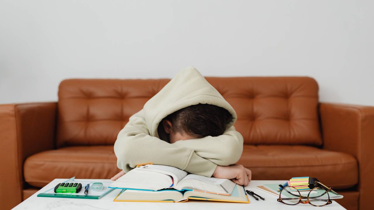 Estudante desmotivado descansa sobre os cadernos