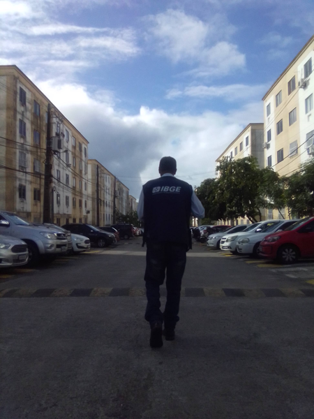 censo-4 Recenseador do IBGE andando no meio de duas fileiras de prédios