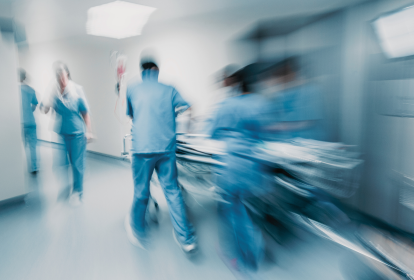 Cena de equipe médica levando uma maca hospitalar por um hospital