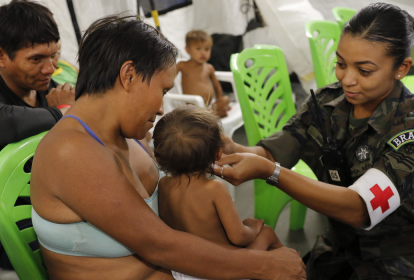 Mãe e criança yanomami são atendidas por agente de saúde.