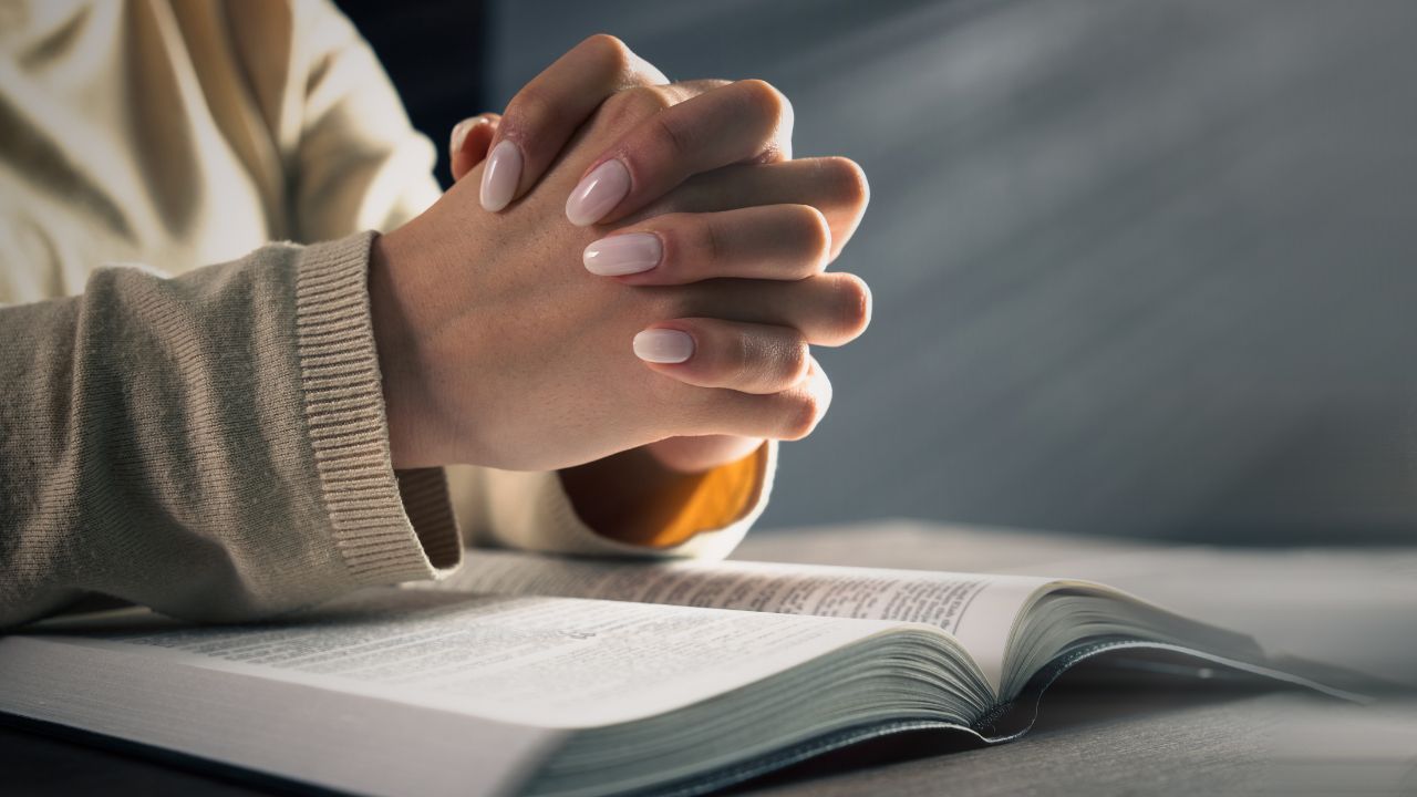 pessoa com mãos juntas rezando