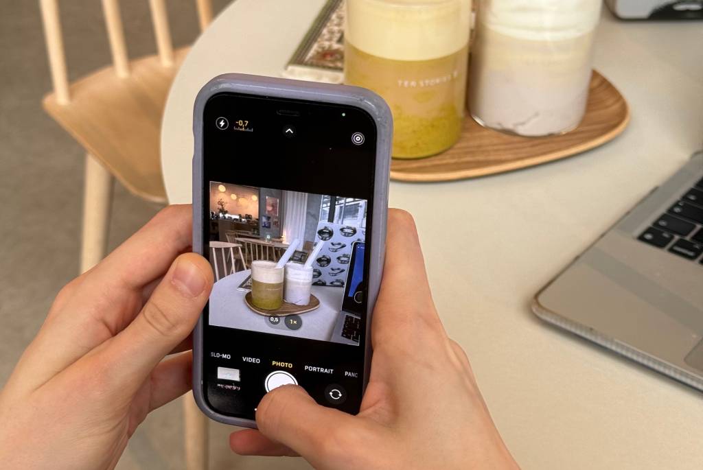 desafio-fotografico pessoa tirando foto com smartphone de dois copos de café em uma mesa