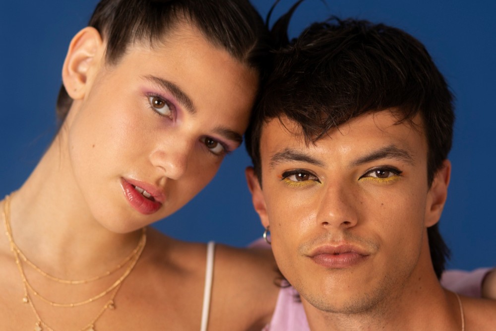 Close-up no rosto de dois modelos: uma mulher e um homem, em fundo liso azul