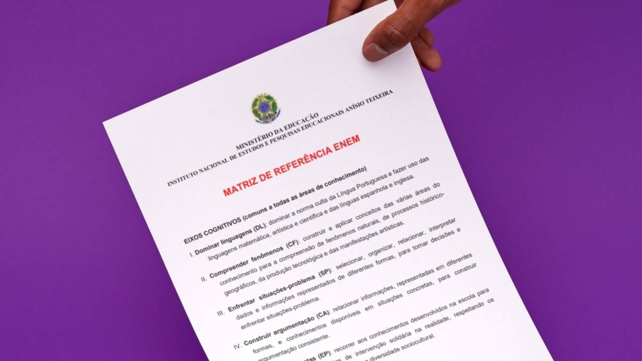 Mão segurando documento com matriz de referência do Enem, contra fundo roxo